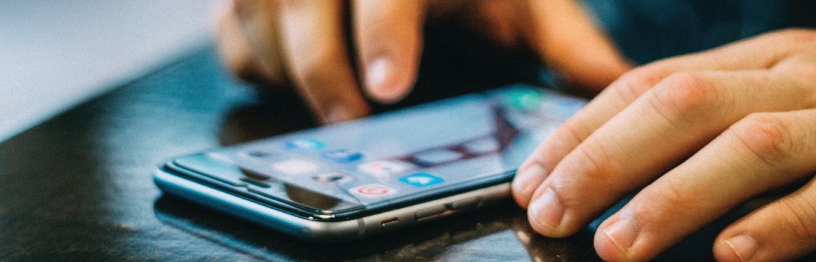 A person's hands using their thumbs to scroll through a smartphone screen.